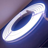 Coiled LED neon glow light strip illuminated in white on dark blue surface