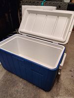 Blue and white Coleman cooler with the lid open, showing clean white interior and hinge on lid