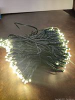 Close-up photo of glowing 200 LED string lights with tightly bundled green wire and small clear bulbs lit up.