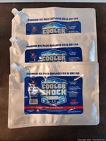 Three Cooler Shock premium reusable ice packs stacked on top of each other, showing the full front label with product and usage information.