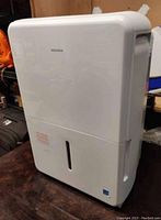 Full view of white Insignia dehumidifier showing front water tank and transparent moisture level window.