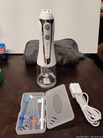 Complete portable H2O flossing kit with device, tips, storage case, and charger arranged on table.