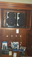 Close-up of Aiwa speakers and Samsung DVD player inside wooden cabinet showing speaker design and connectivity cables.