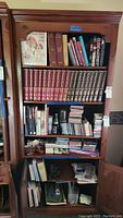 Front view of the full bookcase filled with books and CDs on shelves, showing the overall condition and finish.
