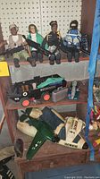 Four G.I. Joe action figures seated on shelf with military vehicles displayed on shelves below.