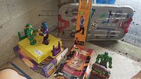 Lot showing multiple toys and games including TMNT Dueling Dudes set, Donatello Bo staff box, Jurassic Park pinball game box, hockey game, and Hulk Bash toy.