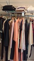 Hanging rack of women's clothing items in size 12 including dresses and tops in pastel and dark shades.