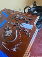 Overview of all jewelry items laid out on table: necklaces, bracelets, brooches, rings, pendants.