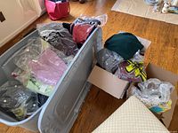 Photo showing bins and boxes containing folded sweaters, many individually sealed in plastic bags.
