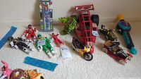 Overview of lot with Power Rangers figures, model cars, and Bop It toy.