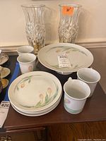 Photo showing the porcelain dessert set of cups, small plates, and cake pedestal plate with tulip floral design along with the two large crystal hurricane candle holders.