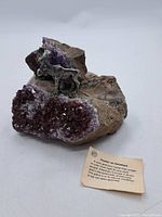 Amethyst geode with attached pewter moose figurine and visible crystal formations.