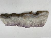 Side view of an amethyst geode slice showing the crystalline purple points and travertine-like base.