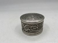 Front side view of lidded trinket dish showing detailed Haida-style engraving on the side.