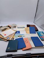Overview of multiple vintage stamp stock books and loose envelopes with stamps scattered around
