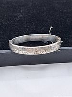 Side view of the bracelet showing detailed floral engraving and inner inscription.