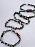 Five turquoise stone beaded bracelets laid out showing variations in bead size, shapes and accent beads.