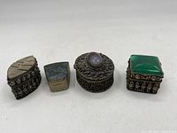 All four small decorative pillboxes in a row showing different shapes and metalwork details