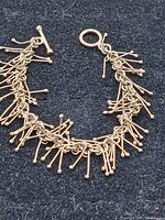 Full view of the sterling silver modernist/brutalist link bracelet showing the toggle clasp and multiple dangling silver rods with rounded ends attached to chain links.