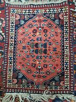 Top-down view showing the entire small vintage hand-knotted rug with central hexagonal medallion and fringed edges.