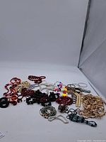Photo showing entire lot of assorted vintage costume jewelry including bracelets, necklaces, and earrings laid out on white background.