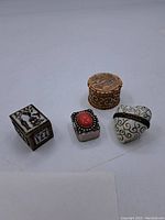 Four pillboxes displayed together on a plain surface showing overall size and design variety.