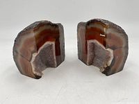 Pair of geode stone bookends shown from front with polished bands and crystalline interiors.