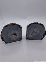 Front view of the pair of geode stone bookends showing the polished crystal-filled interior and rough brown outer edges.