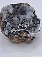 Front close-up of the geode with the pewter horse rider statuette inside, showing crystal formations and statuette details.