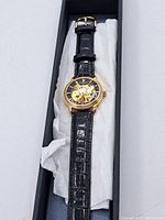 Stratosphere men's automatic wristwatch in original black box, showing full watch with black crocodile-embossed leather strap and gold-tone case.