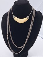 Front view of three necklaces displayed on black bust, showing the crescent-shaped pendant and two silver-tone chains.