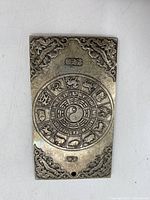 Front side of the ingot showing Chinese zodiac wheel and decorative corners.