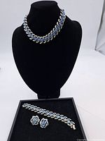 Full set of vintage Coro necklace on black bust, bracelet, and earrings laid flat showing overall design and color