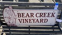 Full front view of Bear Creek Vineyard wood sign showing text and bear climbing tree image.