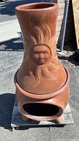Full front view of assembled two-piece chimenea showing sun face design and base opening.
