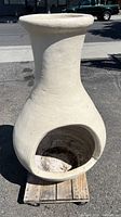 Front view of one-piece chimenea showing bulbous body, wide opening, and tall chimney neck on wooden dolly.