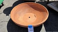 Top down view of large round terra-cotta planter showing overall shape, size, and central drainage hole.