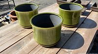 Three green glazed ceramic planters arranged on wooden surface, showing overall size and shape
