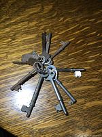 Ring holding a set of eight antique skeleton keys laid out on a wooden surface.