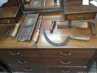 Photo showing the full set of five antique hand tools laid on a wooden dresser surface with visible aged wear.