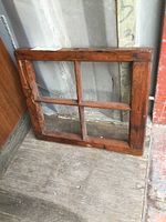 Front view of the antique wooden window frame showing four separate panes and aged wear on the wood.