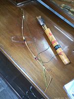 Top-down image of the bow laid on a wooden surface next to the quiver holding arrows