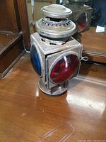 Signal lantern showing angled profile with blue and red lenses on sides and metal top burner.