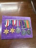 Overall view of all five medals mounted on bar, on purple velvet pad