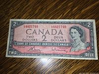 Full front photo of 1954 Canadian two dollar bill displaying serial number, Queen Elizabeth II portrait, and bilingual text.