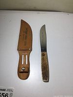 Photo showing full cutter knife next to its leather sheath