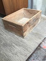 Wooden Winchester crate box showing interior and side with handle cutouts. The wood has aged wear and visible grain.