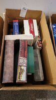 Top-down photo of a cardboard box filled with several board game boxes, showing titles and condition.