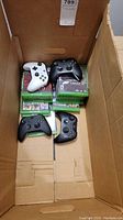 Box interior showing multiple stacked Xbox One game cases and four controllers on top
