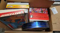 Box of various board games including Scattergories, The Logo Board Game, Battleship, and others stacked inside a larger box.